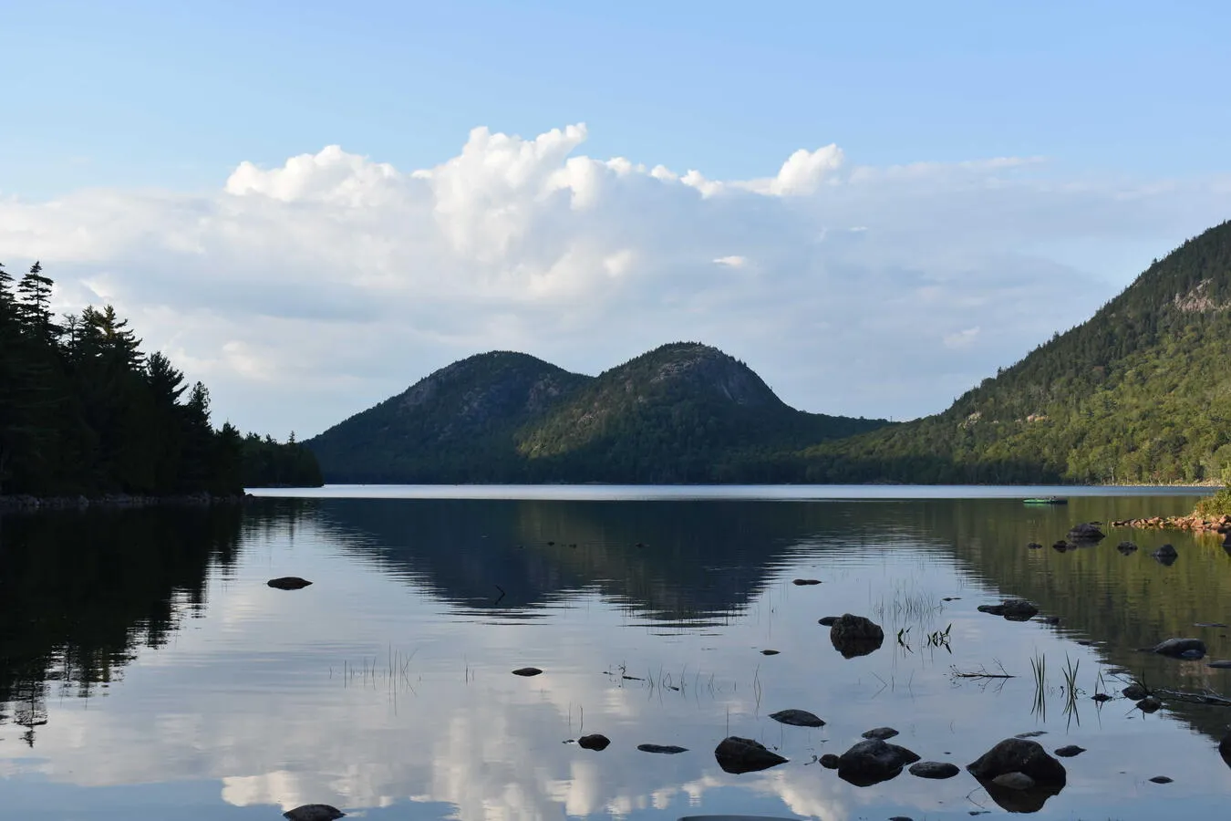 A landscape photo looking out past a lake towards two distant rocky and tree-covered hills, named the "Bubbles".