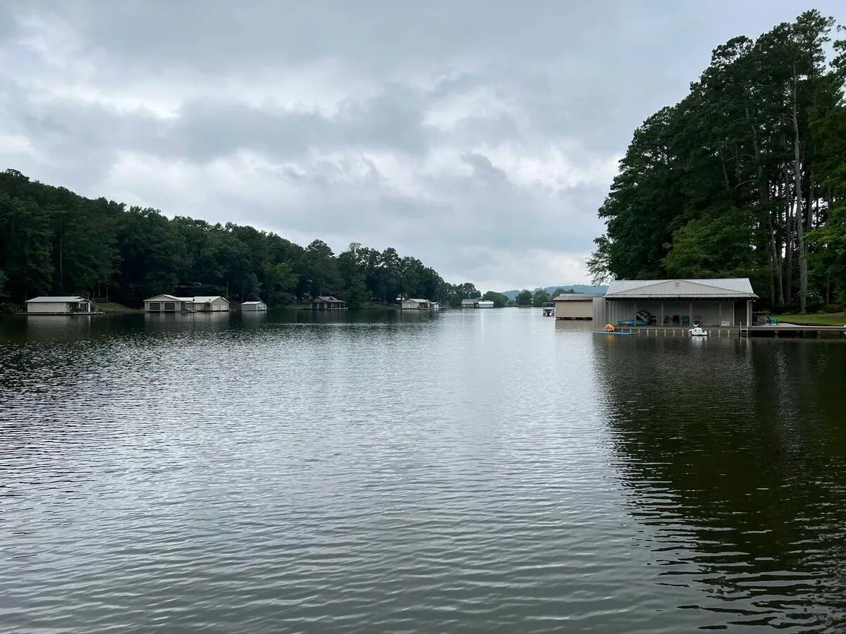 A lake, the shore dotted with docks and related buildings, on an overcast day.