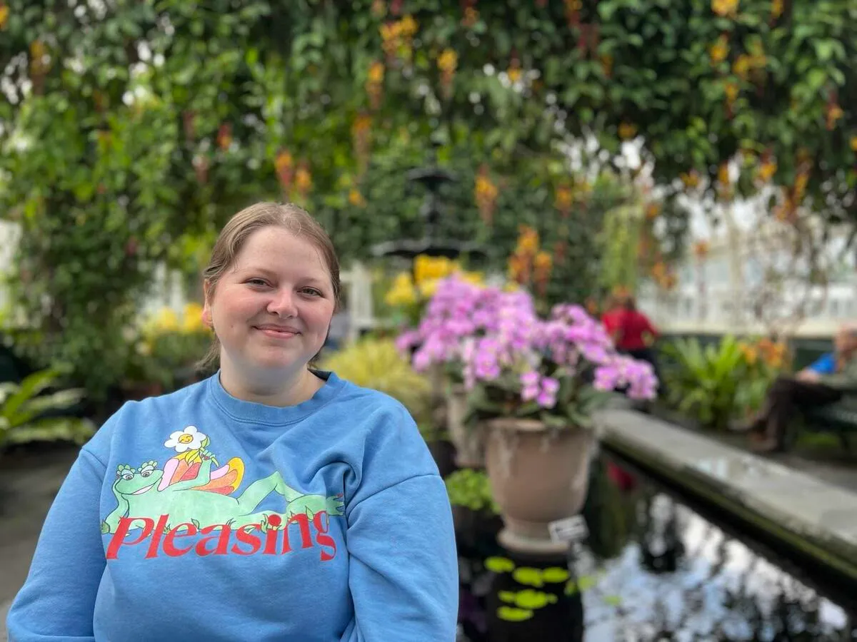 Roxanne in the New York Botanical Garden, surrounded by colorful flowers and greenery.